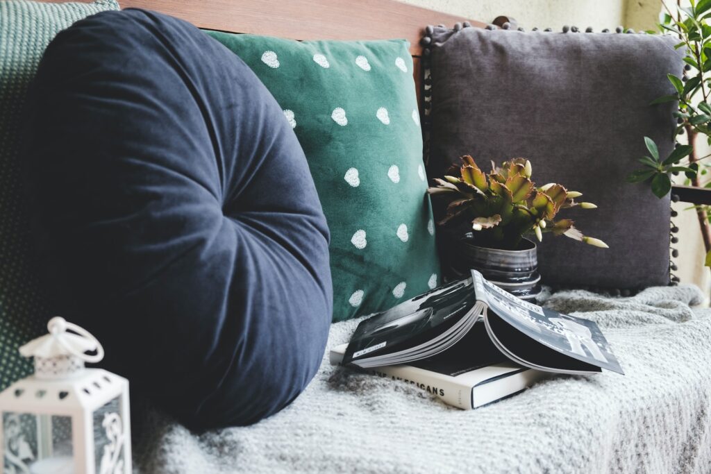 two books beside three assorted-color pillows