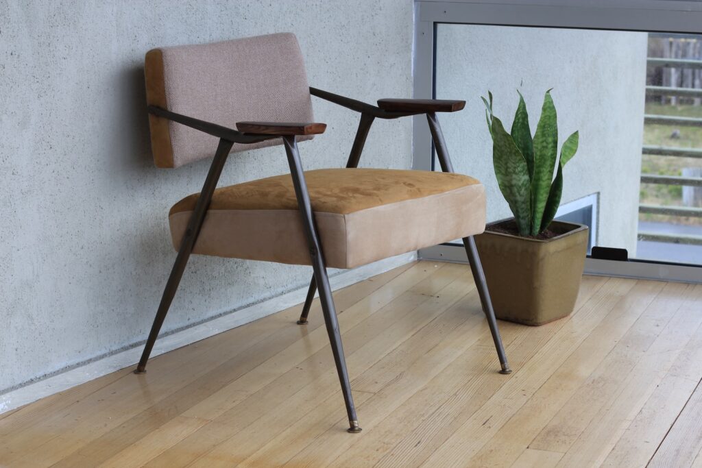 brown fabric padded armchair beside green snake plant inside room